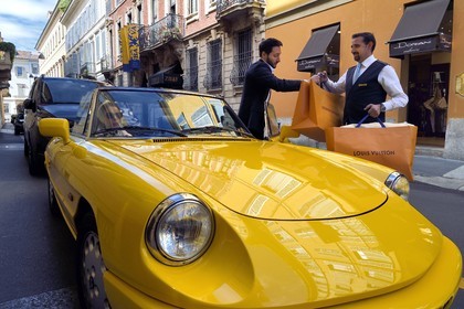 Italie, Lombardie, Milan, Quadrilatère de la Mode (Quadrilatero della moda), cabriolet Alfa Romeo Duetto Spider jaune devant le Four Seasons Hotel Milano, le portier amène un sac Vuitton