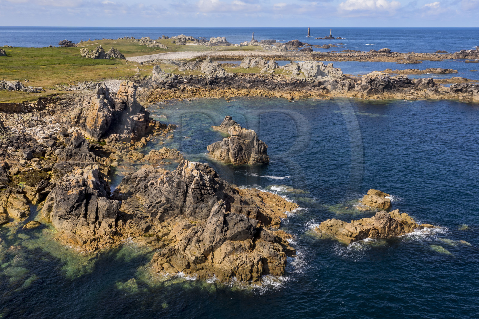 France, Finistère (29), Mer d'Iroise, Ile d'Ouessant, rochers façonnés par les tempêtes au pied du phare du Créac’h, le phare de Nividic sur la Pointe de Pern en arrière plan (vue aérienne)