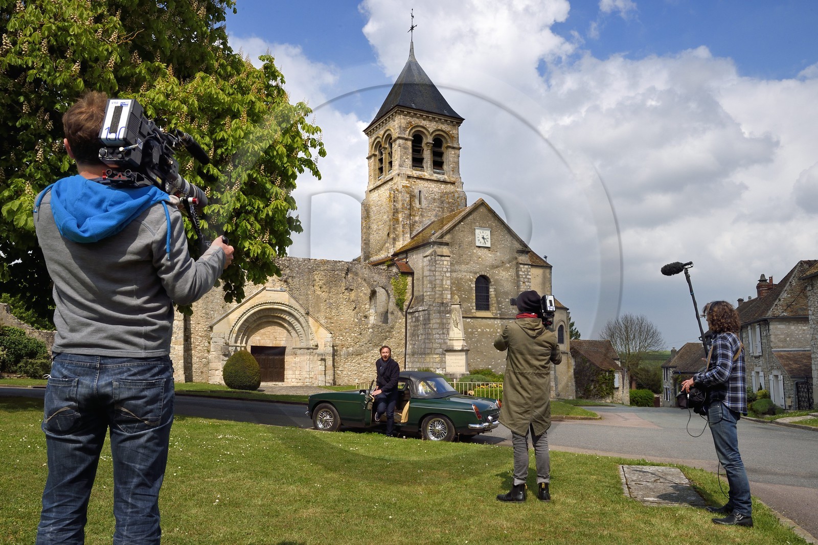 France, Yvelines (78), Montchauvet, tournage pour la télévision du Village Préféré des Français avec Stéphane Bern, Stéphane Bern au volant d'une MG cabriolet devant l'église Sainte Marie-Madeleine