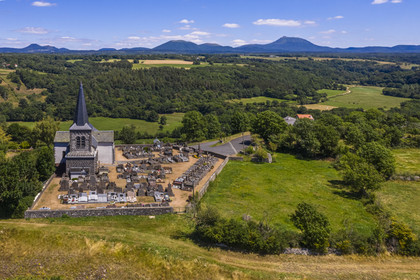 France, Puy-de-Dôme (63), église sur la butte basaltique de Saint-Pierre-Le-Chastel surplombant la vallée de la Sioule, la Chaîne des Puys classée Patrimoine Mondial de l’UNESCO, avec le Puy de Côme à gauche, le Grand Suchet et le volcan Puy de Dôme à droite (vue aérienne)
