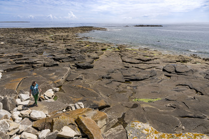 France, Finistère (29), Mer d'Iroise, Ile de Molène, Christine Demeure qui gère la seule épicerie de l'ile lors de sa promenade quotidienne sur la côte sauvage à l'Ouest, grève des Pierres Plates qui a servi de carrière
