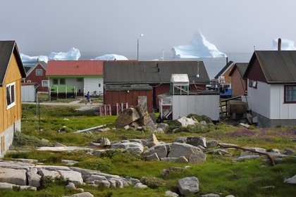 Groenland, cote ouest, Ile de Disko, maisons du village de Qeqertarsuaq et icebergs en arrière plan