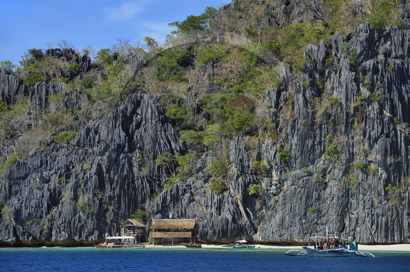 Philippines, Calamian Islands dans le nord de Palawan, Coron Island Natural Biotic Area, pirogue à balancier et plage au pied des murs géants des falaises de calcaire