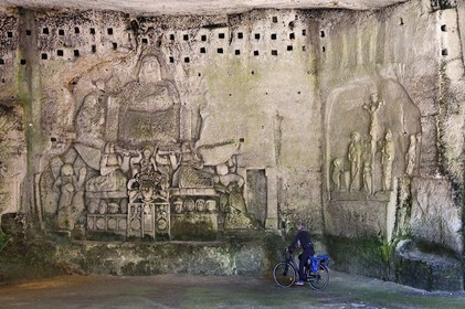 France, Dordogne (24), Brantôme, l'abbaye bénédictine Saint-Pierre de Brantôme, vestiges du premier monastère troglodytique aménagé dans les grottes au pied de la falaise avec notamment dans la grotte du Jugement Dernier, à droite la Crucifixion du début XVIIème siècle, à gauche un bas relief du XV ème siècle sous le pigeonnier, cycliste sur la véloroute la Flow Vélo