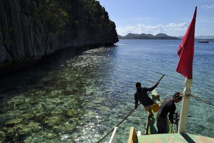 Philippines, Calamian Islands dans le nord de Palawan, Coron Island Natural Biotic Area, pirogue à balancier au pied des rochers de calcaire dans une petite crique