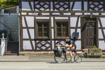 France, Bas-Rhin (67), Parc naturel régional des Vosges du Nord, Niedersteinbach, trottinettes à grandes roues tout terrain devant une maison traditionnelle à pans de bois dans la rue principale