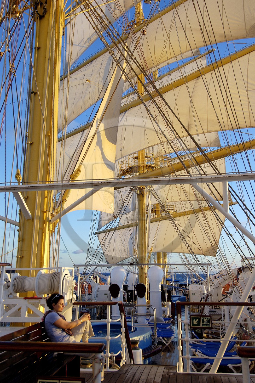 Caraïbes, le SPV Royal Clipper toutes voiles dehors, une passagère contemple le lever de soleil sur le pont supérieur