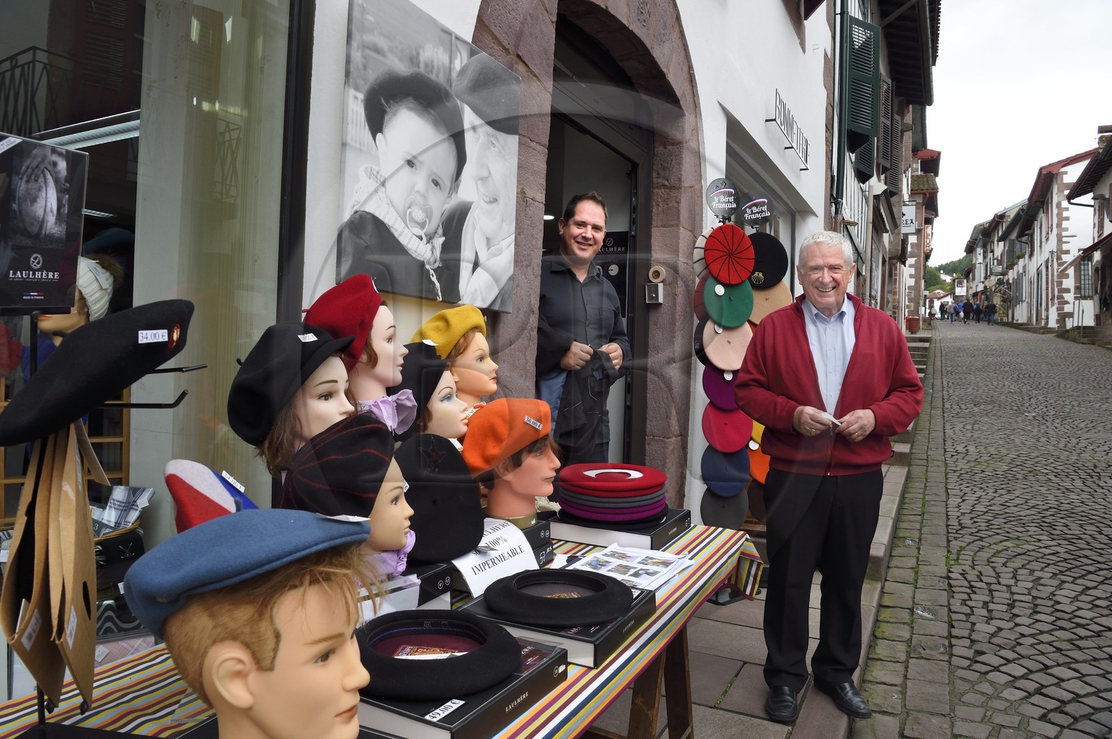 France, Pyrénées-Atlantiques (64), Pays-Basque, Saint-Jean-Pied-de-Port, rue d'Espagne sur le chemin de Saint-Jacques-de-Compostelle, l'ancien champion de pelote grand chistera Michel Cavier et son père Jean Cavier à droite devant leur boutique de vêtements