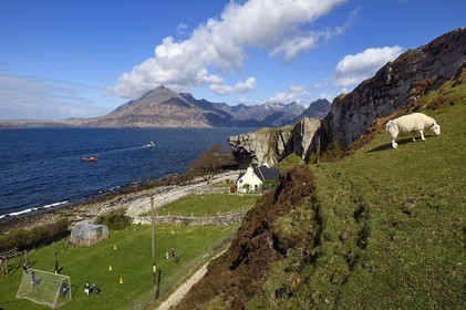 Royaume-Uni, Ecosse, région des Highlands, les Hébrides, Ile de Skye, village de Elgol sur les rives du Loch Scavaig au bout de la péninsule de Strathaird et le massif des Black Cuillin Mountains en arrière plan, enfants jouant au rounders dans le jardin de l'école
