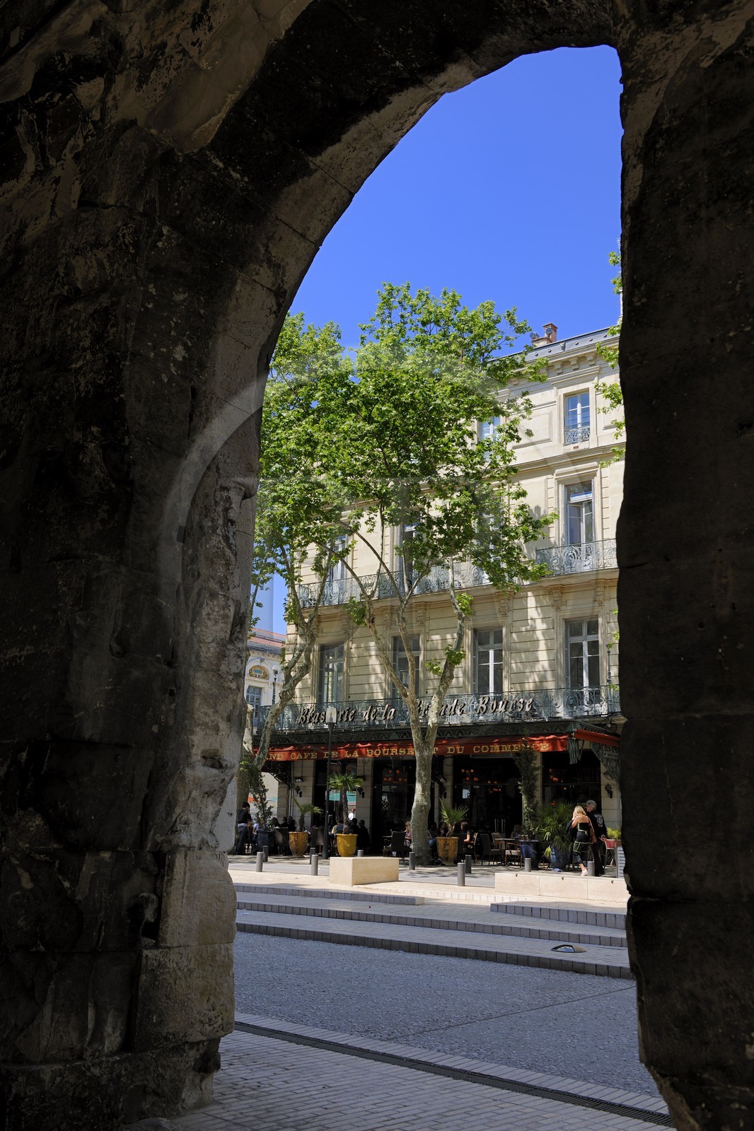 France, Gard (30), Nimes, brasserie boulevard des arènes au travers d'une arcade des arènes