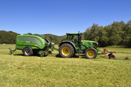 France, Puy-de-Dôme (63), Saint-Ours-les-Roches, hameau de Beauregard, tracteur récoltant le fourrage avec une presse enrubanneuse de balles de foin dans un champ