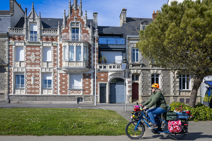 France, Loire-Atlantique (44), Saint-Nazaire, boulevard du Président Wilson sur le front de mer, cycliste utilisant un Velycéo avec son chien passant devant une des maisons épargnées par les bombardements de la deuxième guerre mondiale