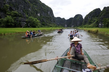 Vietnam, province de Ninh Binh, région surnommée la baie d'Halong terrestre, excursion en barque à Tam Coc entouré de montagnes karstiques , ramant avec ses pieds