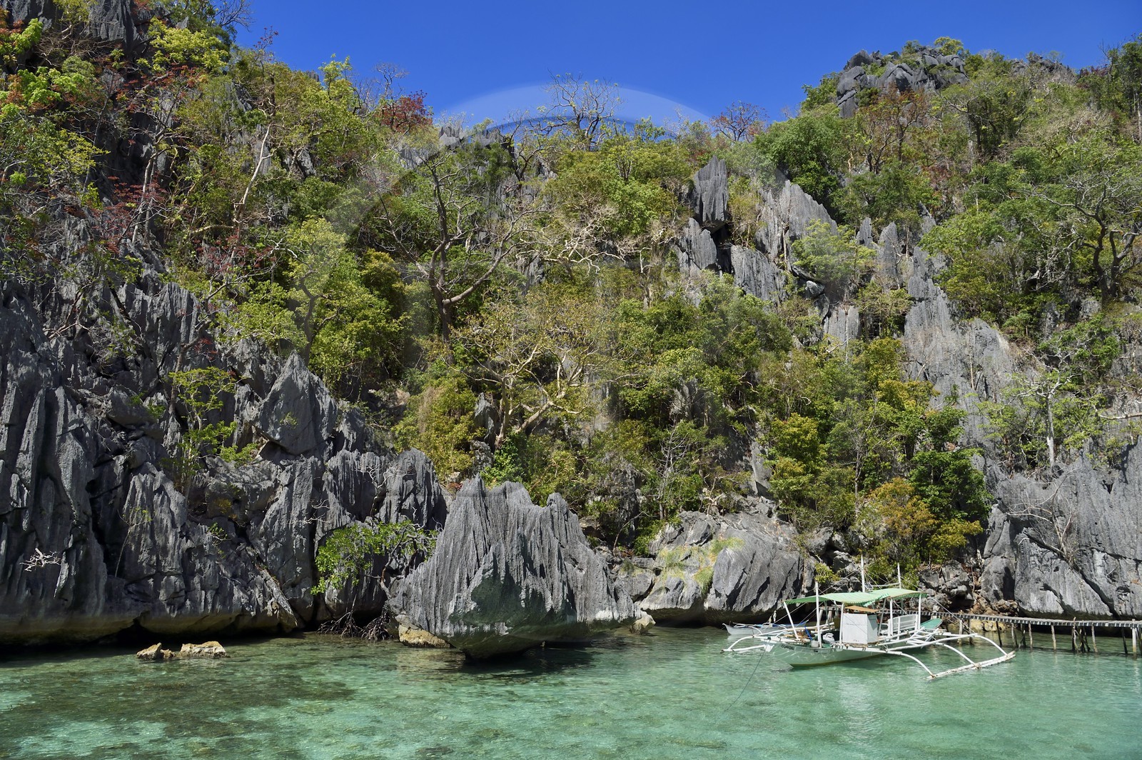 Philippines, Calamian Islands dans le nord de Palawan, Coron Island Natural Biotic Area, pirogue à balancier au pied des rochers de calcaire