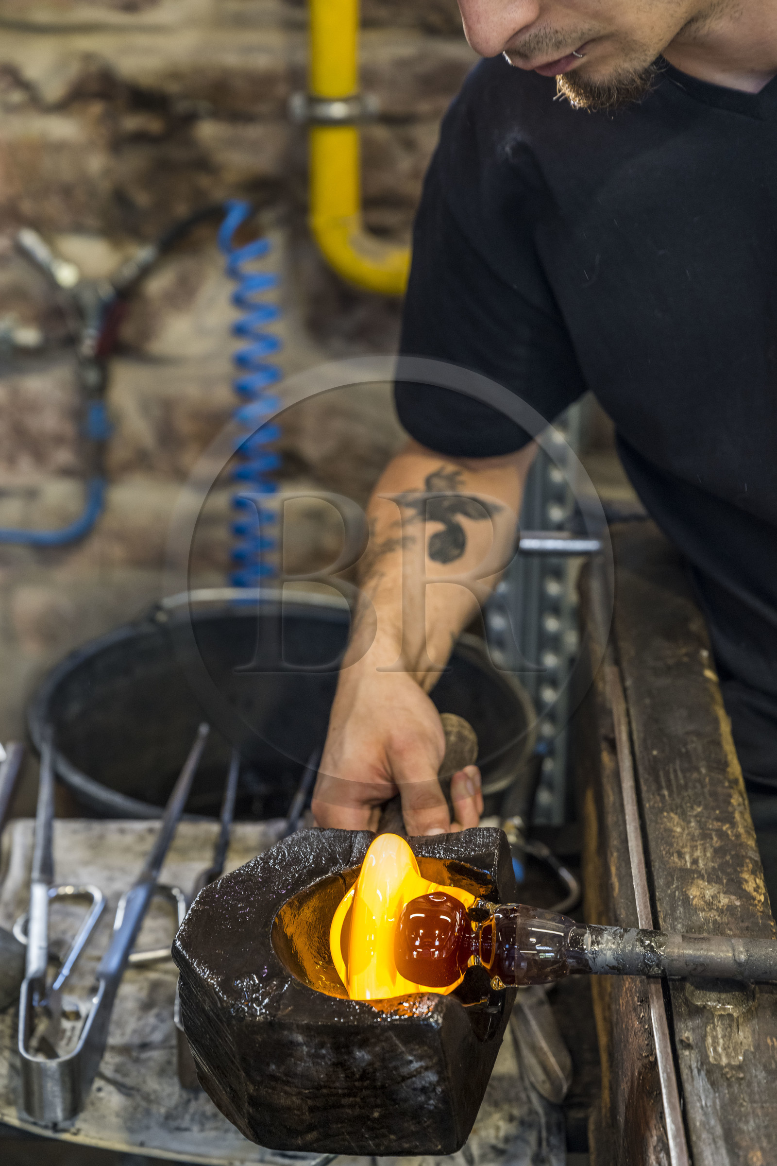 France, Moselle (57), Meisenthal, Centre international d’Art verrier (CIAV), l'atelier de soufflage, le souffleur régularise la masse au marbre tout en effectuant une rotation continue de sa canne et préparation de la paraison avant le passage au moule