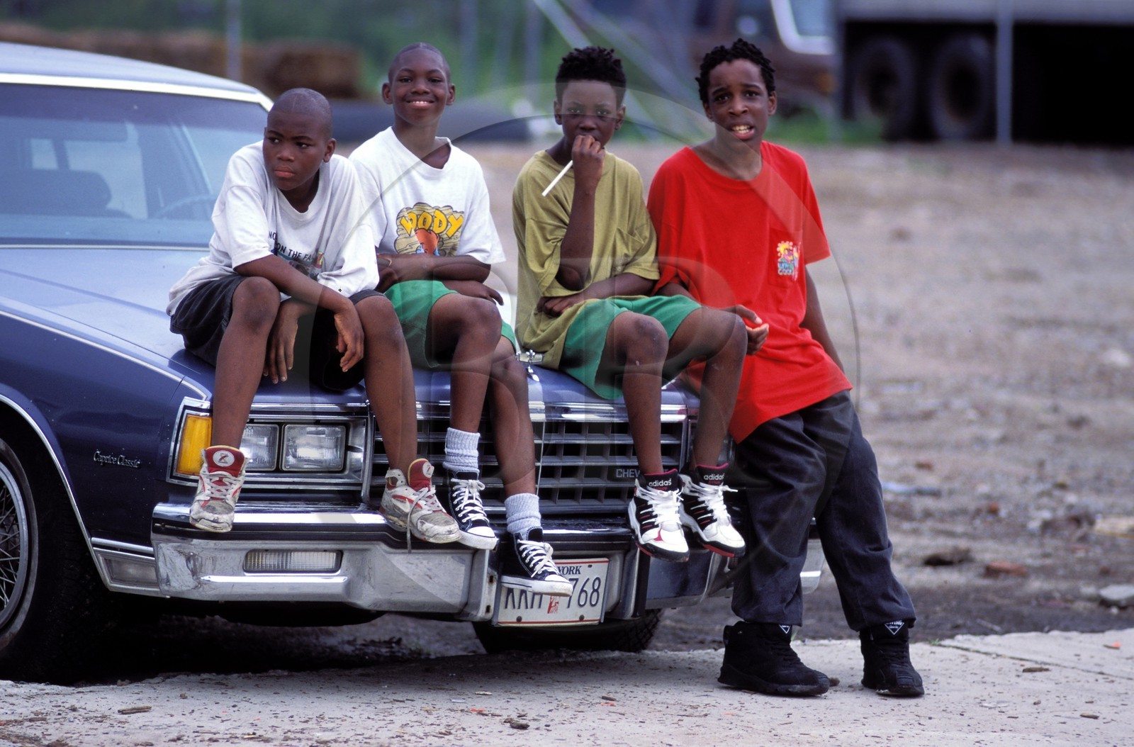 Etats-Unis, New York, Manhattan, groupe d'enfants d'un quartier difficile assis sur le capot d'une voiture