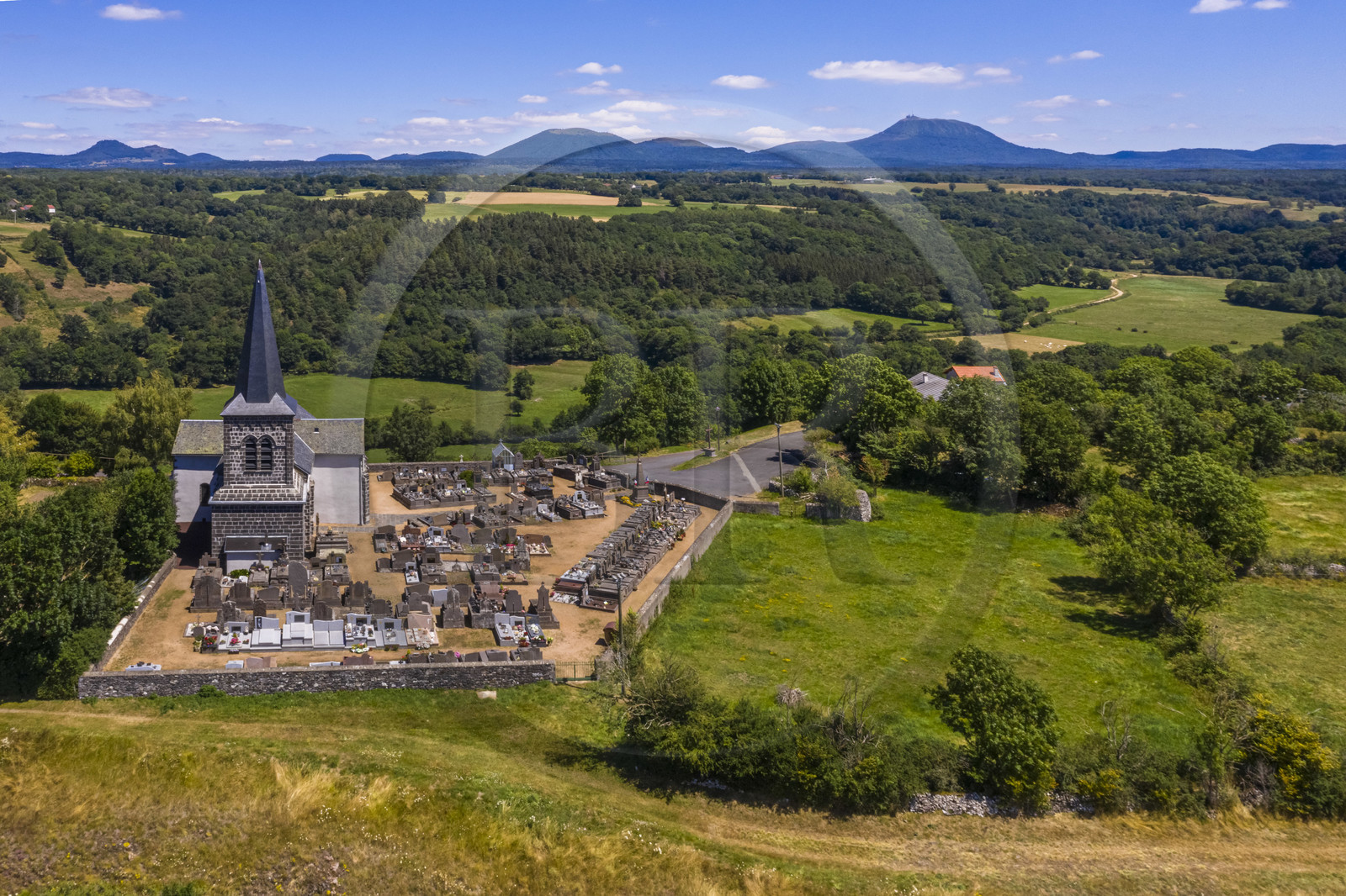 France, Puy-de-Dôme (63), église sur la butte basaltique de Saint-Pierre-Le-Chastel surplombant la vallée de la Sioule, la Chaîne des Puys classée Patrimoine Mondial de l’UNESCO, avec le Puy de Côme à gauche, le Grand Suchet et le volcan Puy de Dôme à droite (vue aérienne)