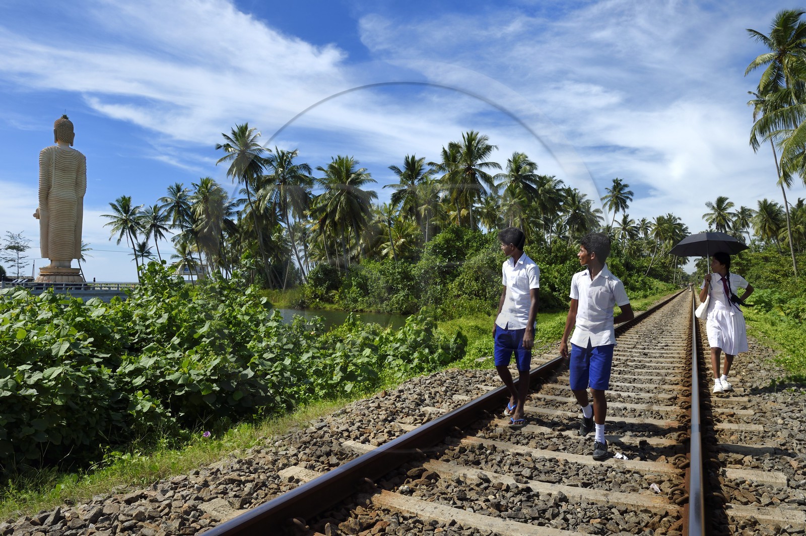 Sri Lanka, Province du Sud, region de Galle, Telwatta, écoliers marchant sur la voie ferrée de Colombo à Galle devant le Bouddha de Peraliya en memoire des nombreuses victimes du train bondé emporté par le Tsunami du 26 décembre 2004