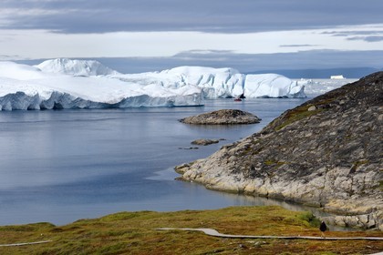 Groenland, cote ouest, baie de Disko, Ilulissat, fjord glacé classé Patrimoine Mondial de l'UNESCO qui est l’embouchure maritime du glacier Sermeq Kujalleq (Jakobshavn Glacier), passerelle en bois du chemin de randonnée allant sur le site de Sermermiut et bateau de pêche au pied des icebergs