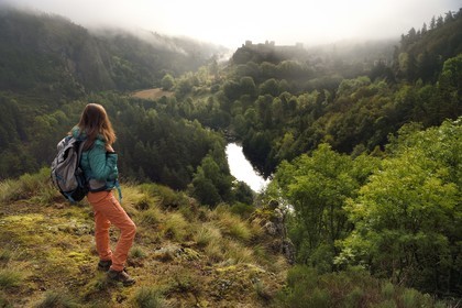 France, Haute-Loire (43), vallée de la Loire, Arlempdes, labellisé les Plus beaux villages de France, randonneuse observant les ruines du chateau perché sur un rocher basaltique qui surplombe un méandre de la Loire