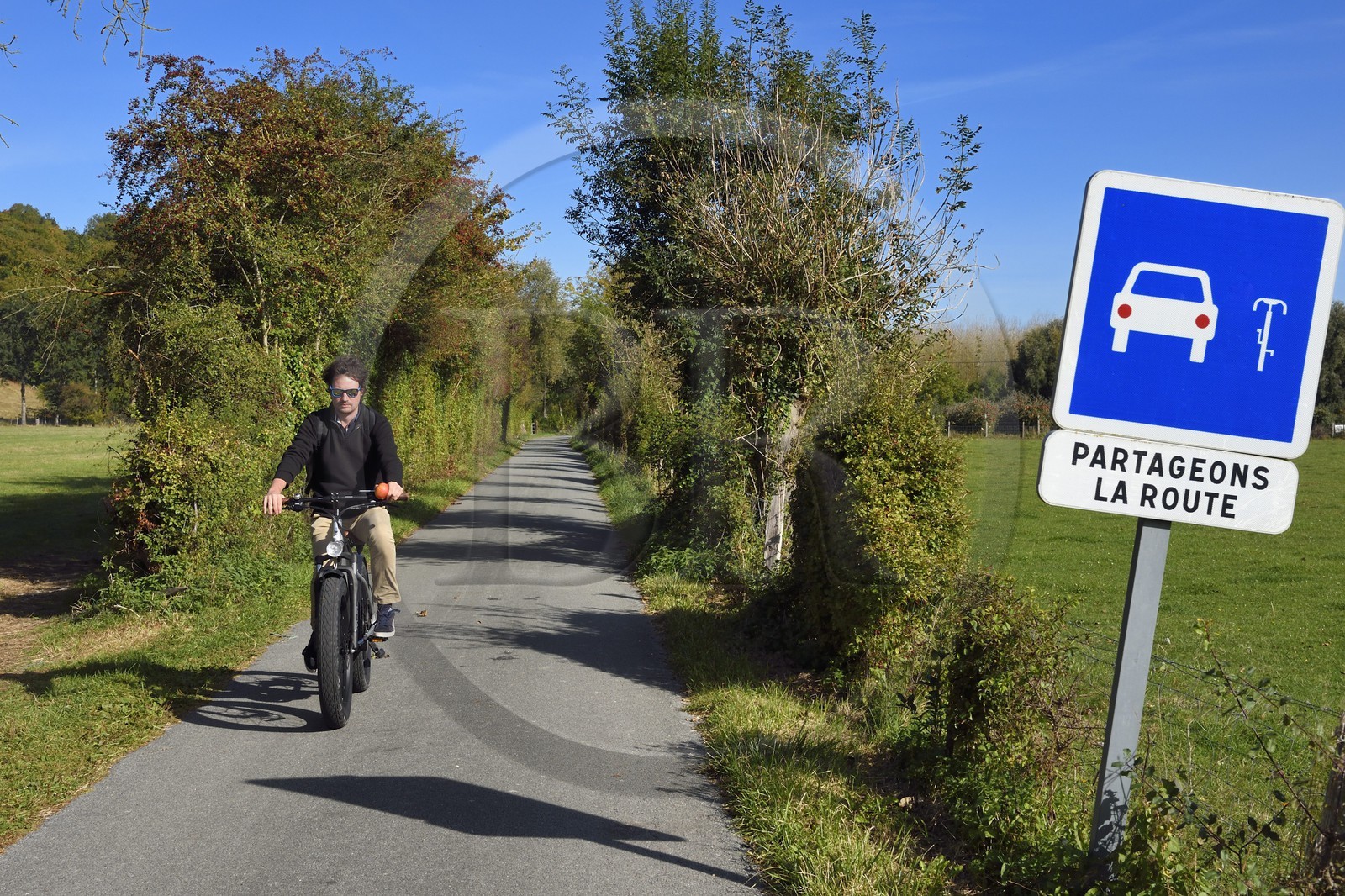 France, Seine-Maritime (76), Parc naturel régional des Boucles de la Seine normande, Bardouville, cycliste sur la veloroute du Val de Seine avec panneau Partageons la Route
