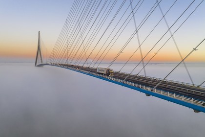 France, entre Calvados (14) et Seine-Maritime (76), le Pont de Normandie émerge des brumes matinales de l'automne et enjambe la Seine pour relier les villes de Honfleur et du Havre