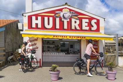 France, Vendée (85), île de Noirmoutier, La Guérinière, cyclistes devant un ostréiculteur au Port de Bonhomme
