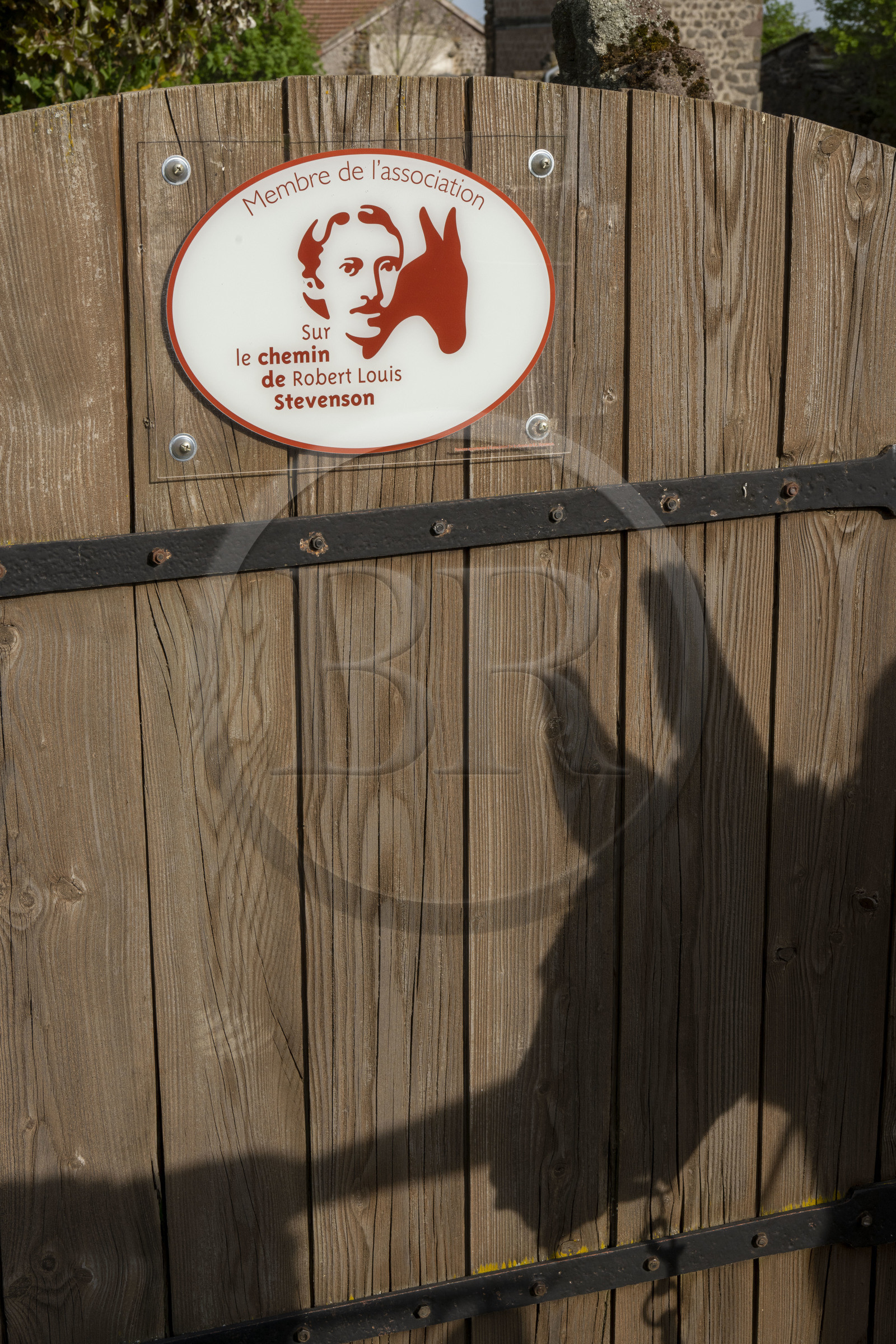 France, Haute-Loire (43), Bouchet-Saint-Nicolas, randonnée avec un âne sur le chemin de Stevenson (GR 70), panneau indiquant un membre de l'association du Chemin de Stevenson et ombre projeté de l'âne Anatole