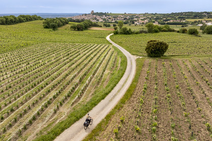France, Vaucluse (84), Châteauneuf-du-Pape, randonnée à vélo sur le chemin Coste Froide sur le plateau de la Crau et le donjon de Châteauneuf-du-Pape en arrière plan (vue aérienne)