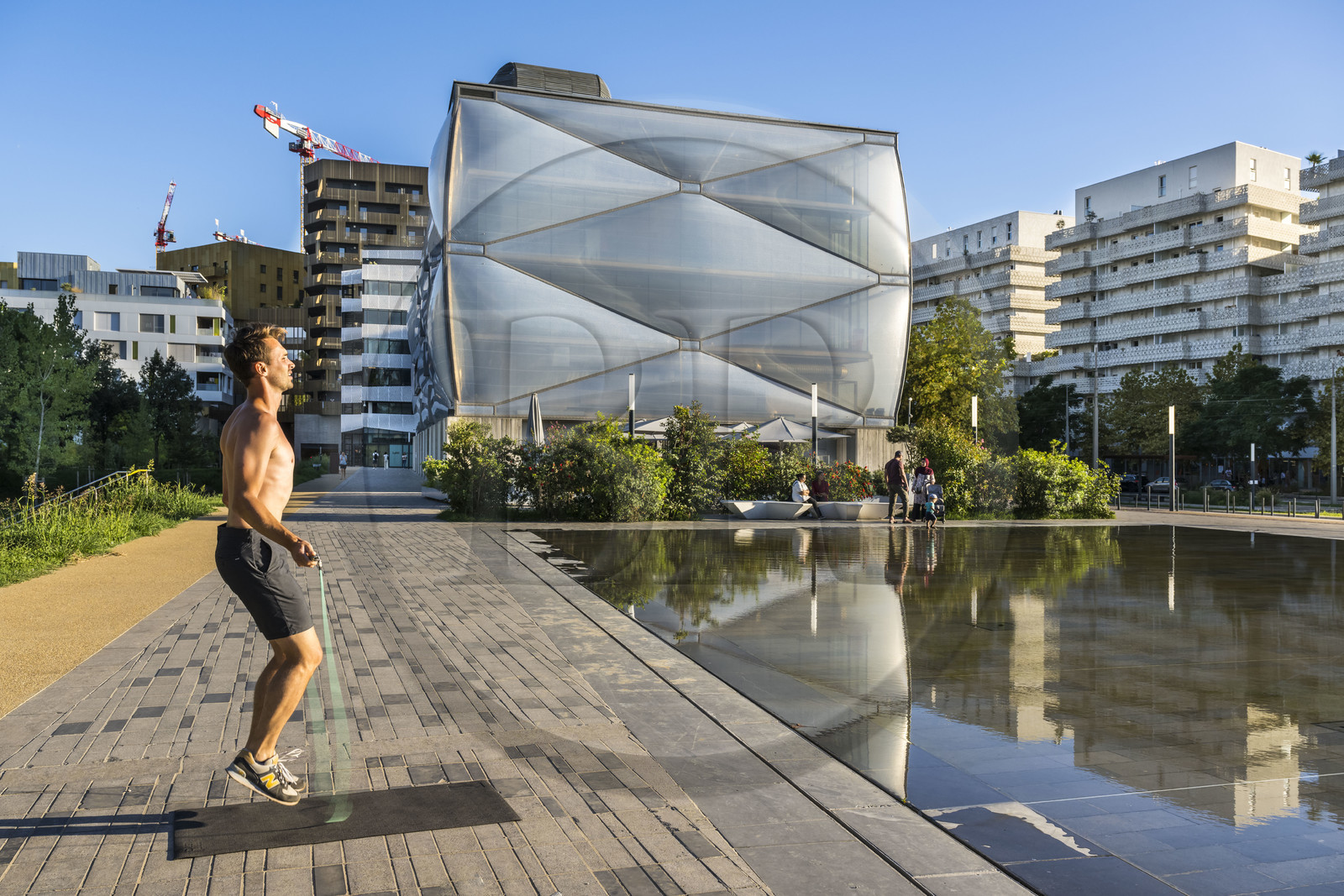 France, Hérault (34), Montpellier,  quartier de Port Marianne, batiment le Nuage réalisation du créateur Philippe Starck, sportif à la corde à sauter devant le miroir d'eau au premier plan sur l'avenue Raymond Dugrand