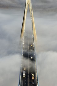France, entre Calvados (14) et Seine-Maritime (76), le Pont de Normandie qui émerge des brumes matinales de l'automne et enjambe la Seine, vue depuis le sommet du pylone sud