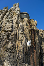 France, Finistère (29), Mer d'Iroise, Ile d'Ouessant, rochers façonnés par les tempêtes au pied du phare du Créac’h, échelle menant au batiment de l'ancienne corne de brume (vue aérienne)
