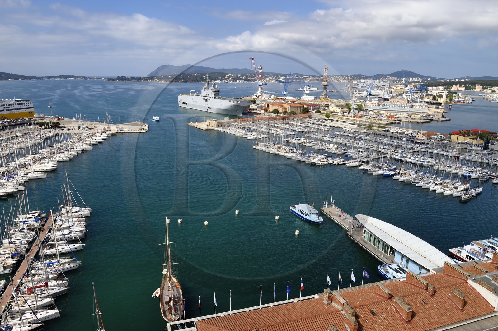 France, Var (83), Toulon, embarcadère de bateau-bus de la Station maritime quai Cronstadt sur le port civile, le Mistral (L9013) porte-hélicoptères amphibie de la Marine nationale française en arrière plan dans la base navale (Arsenal)
