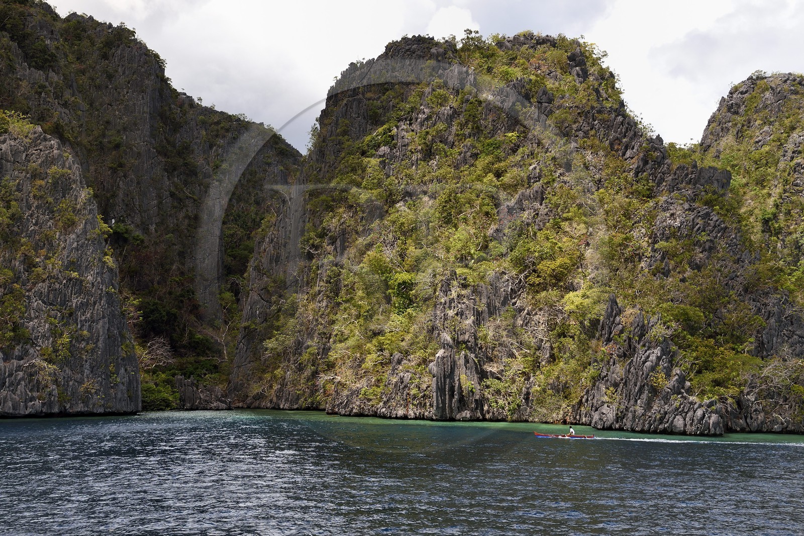 Philippines, Calamian Islands dans le nord de Palawan, Coron Island Natural Biotic Area, pirogue à balancier dans un lagon au pied des falaises de calcaire du Permien d'origine jurassique