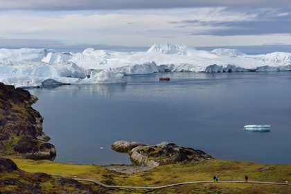 Groenland, cote ouest, baie de Disko, Ilulissat, fjord glacé classé Patrimoine Mondial de l'UNESCO qui est l’embouchure maritime du glacier Sermeq Kujalleq (Jakobshavn Glacier), passerelle en bois du chemin de randonnée allant sur le site de Sermermiut et bateau de pêche au pied des icebergs