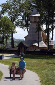 Pologne, Petite Pologne, Carpates, paysanne et sa petite fille tirant une charrette de foin devant l' église en bois Saint-Nicolas (15e siècle) classée Patrimoine Mondial de l'UNESCO dans le village de Debno