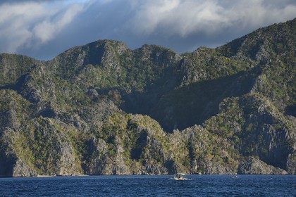 Philippines, Calamian Islands dans le nord de Palawan, Coron Island Natural Biotic Area, pirogue à balancier au pied des murs géants des falaises de calcaire du Permien d'origine jurassique