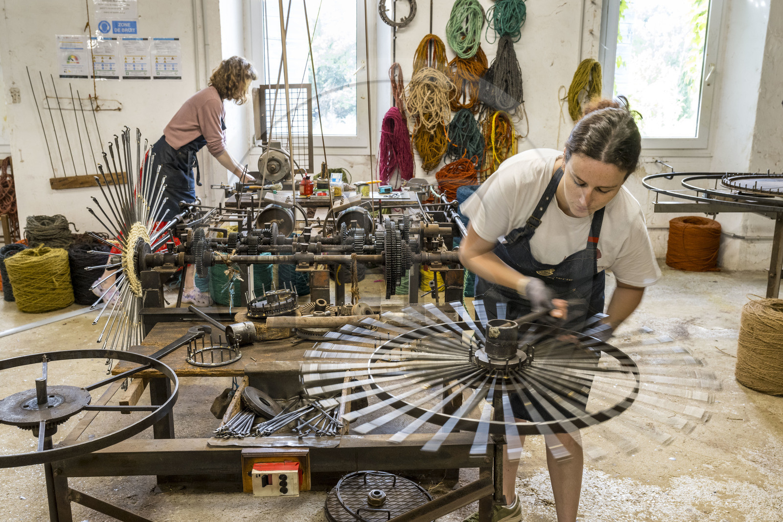 France, Drôme (26), Drôme provençale, Nyons, La Scourtinerie, dernière manufacture de scourtins de Provence, filtres traditionnels utilisés dans la fabrication de l'huile d'olive mais conçus aussi aujourd'hui comme objets de décoration en fibre de coco, fabrication de scourtins dans leur atelier sur des machines faites sur mesure, Sophie Villeneuve-Fert procède aux réglages d'un des appareils à tisser circulaires au poste de montage des aiguilles