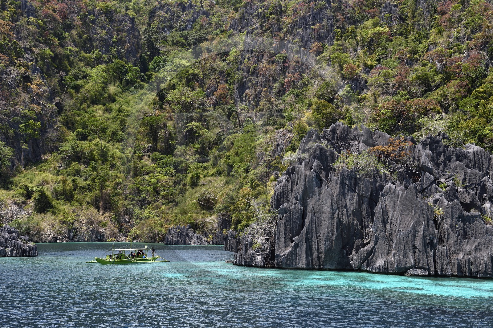 Philippines, Calamian Islands dans le nord de Palawan, Coron Island Natural Biotic Area, pirogue à balancier dans un lagon au pied des falaises de calcaire du Permien d'origine jurassique