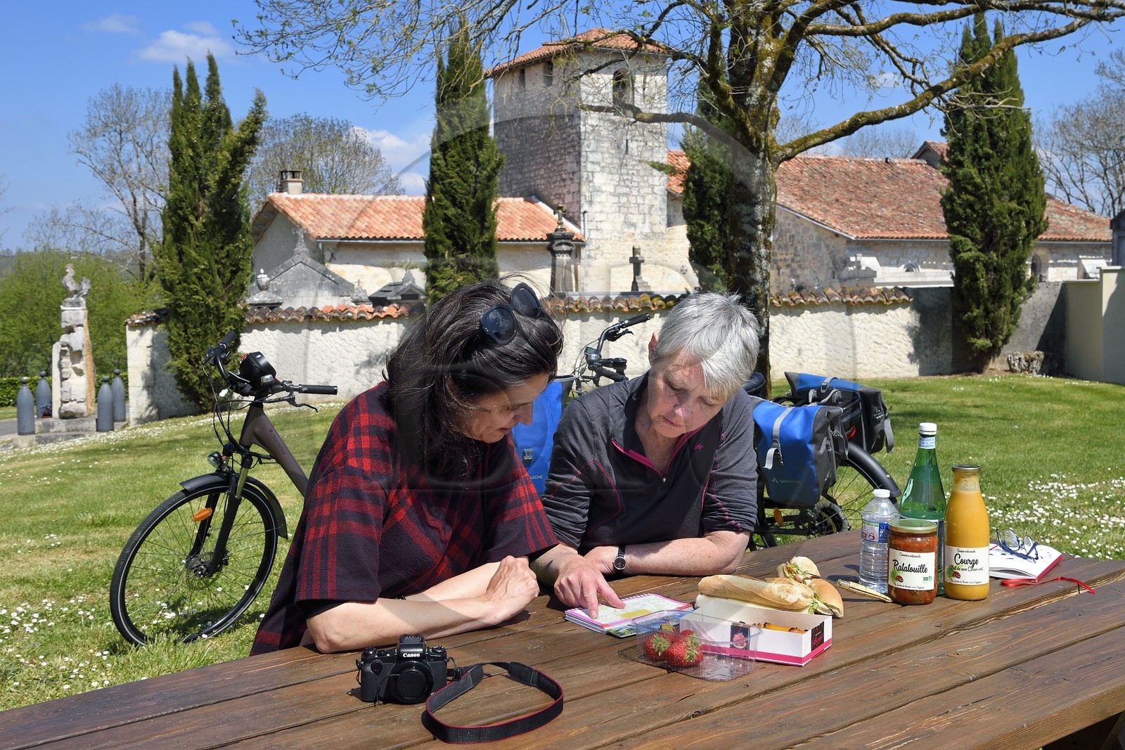 France, Charente (16), Souffrignac, pique-nique de cyclistes sur la véloroute la Flow Vélo aux Jardins du Bandiat, l'église romane Saint-Antoine du XIIème siècle en arrière plan