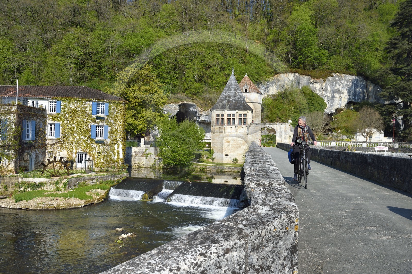 France, Dordogne (24), Brantôme, Pont Coudé sur la Dronne et le Moulin de L'Abbaye à gauche, ancien moulin du XVIe siècle transformé en Hotel****-Restaurant de charme, le pavillon Renaissance et la tour qui formaient la porte fortifiée en arrière plan, cyclistes sur la véloroute la Flow Vélo