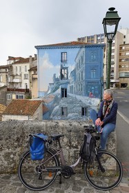 France, Charente (16), Angoulême, Boulevard Pasteur dans le centre historique, cycliste faisant la véloroute La Flow Vélo devant La fille des Remparts, mur peint d'après un dessin original de Max Cabanes et réalisé par la Cité de la création en 2004