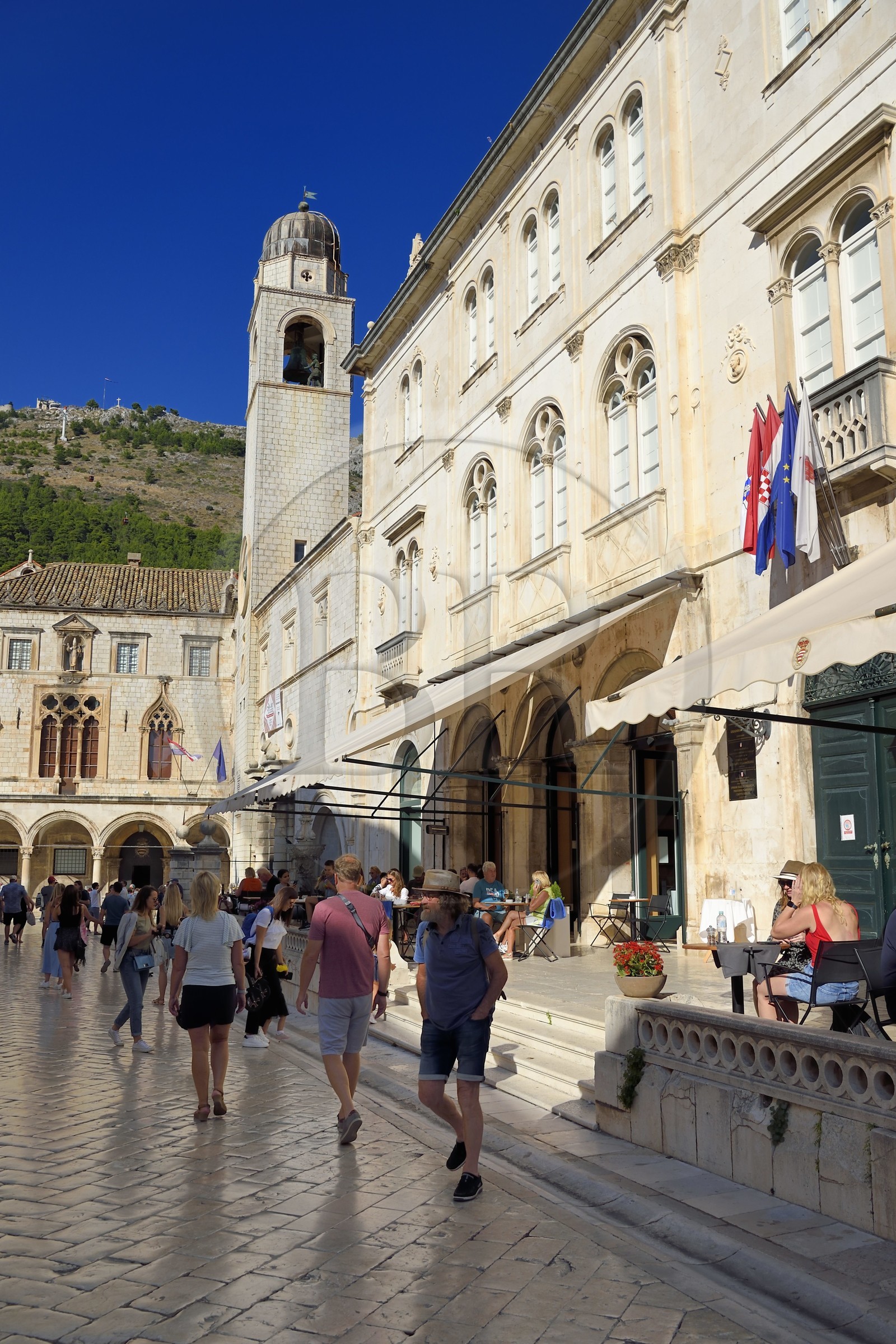 Croatie, Dalmatie, cote dalmate, Dubrovnik, centre historique classé Patrimoine Mondial de l'UNESCO, place Luza au bout du Stradun et la Tour de l'horloge, à droite le Gradska kavana Arsenal restaurant sur la place Pred Dvorom