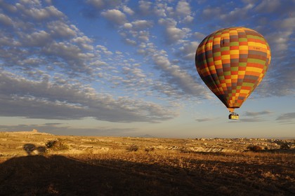 Turquie, Anatolie Centrale, province de Nevsehir, Cappadoce classée Patrimoine Mondial de l'UNESCO, vol d'une montgolfière avec le rocher d'Uçhisar au fond