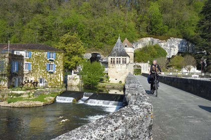 France, Dordogne (24), Brantôme, Pont Coudé sur la Dronne et le Moulin de L'Abbaye à gauche, ancien moulin du XVIe siècle transformé en Hotel****-Restaurant de charme, le pavillon Renaissance et la tour qui formaient la porte fortifiée en arrière plan, cyclistes sur la véloroute la Flow Vélo