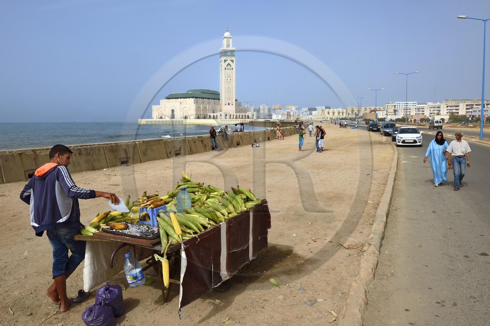Maroc, Casablanca, vendeur ambulant de maïs grillé devant la Grande Mosquée Hassan II