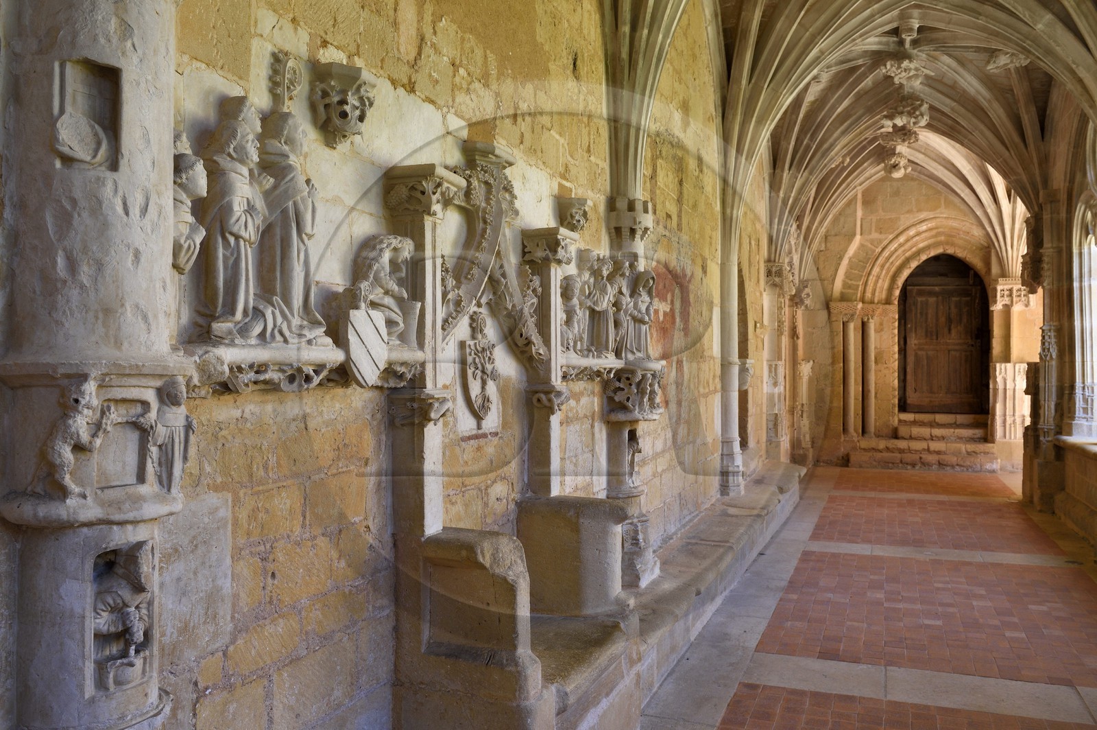 France, Dordogne (24), Périgord Noir, Le Buisson-de-Cadouin, abbaye de Cadouin, étape sur le chemin de Compostelle, site classé Patrimoine Mondial de l'UNESCO, le cloitre du XVe siècle, bas-relief de la passion du Christ, le banc des moines avec le siège de l'Abbé et Porte Romane en arrière plan