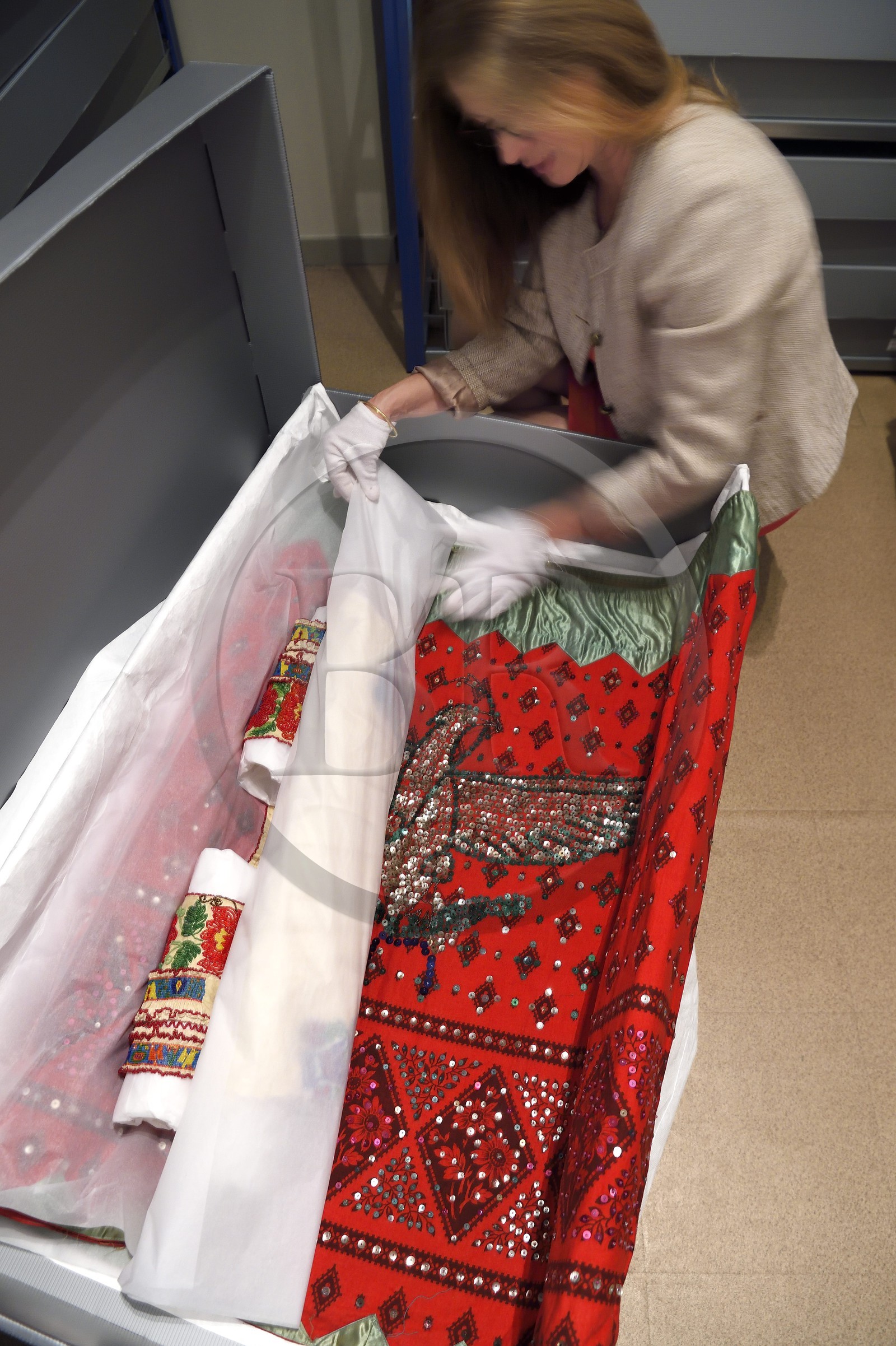 France, Alpes-de-Haute-Provence (04), vallée de l'Ubaye, Barcelonnette, villa mexicaine connue sous le nom de Villa Sapinière, Musée de la vallée, la conservatrice Hélène Homps dans la réserve du musée observe une robe brodée China poblana, costume national mexicain porté par les épouses des barcelonnettes pour le 14 juillet au Mexique