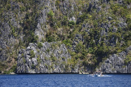 Philippines, Calamian Islands dans le nord de Palawan, Coron Island Natural Biotic Area, pirogue à balancier au pied des murs géants des falaises de calcaire
